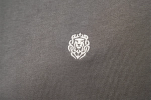 Close-up of premium lion head embroidery on dark grey cotton polo shirt fabric