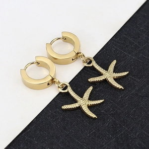 Detail of gold starfish drop earrings with textured surface and huggie hoop closure