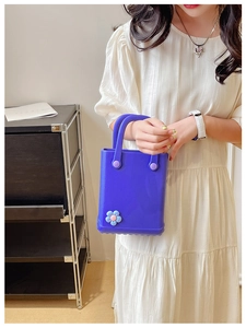 Detail der dunkelblauen EVA-Tasche mit 3D-Blume, getragen von einer Frau im weißen Kleid