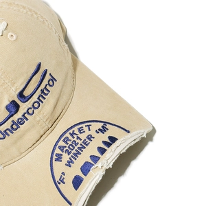 Detailed macro shot of vintage embroidery and distressed brim on a khaki baseball cap