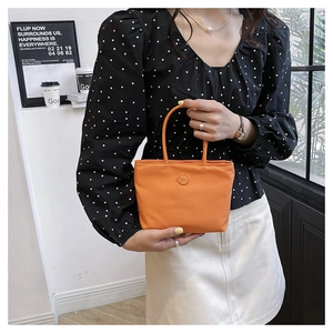 Sac seau chic en nylon orange avec emblème lettre m circulaire porté par une femme