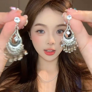 Close-up of retro silver shell tassel earrings with rhinestones and vintage drop details
