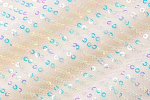 Close-up of white mesh fabric with laser iridescent sequins in a striped pattern