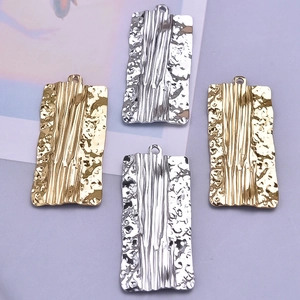 Detail of 18k gold and silver rectangular metal pendants with wrinkled foil texture