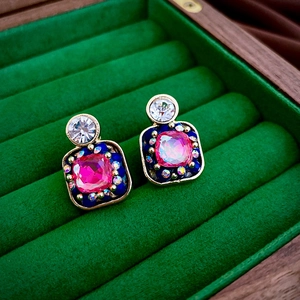 Macro detail of vintage square earrings with pink gems and blue beads in a velvet box