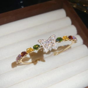 Macro di bracciale a farfalla dorato con gemme colorate su vassoio per gioielli in velluto