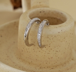 Close-up of S925 silver C-shaped earrings featuring micro-pave zirconia on a ceramic edge