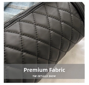 Macro detail of black quilted nylon cylinder bag with diamond stitching and zipper closure