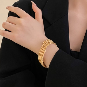 Detail of layered gold beaded bracelet worn on wrist for a minimalist luxury aesthetic