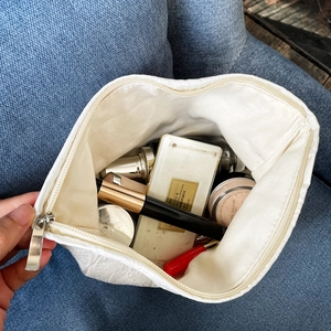 Top view of white textured rose jacquard cosmetic bag showing large capacity with makeup tools