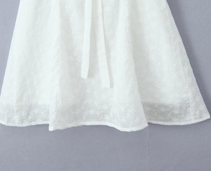 Detailed close-up of white floral embroidery and delicate lace texture on the skirt hem