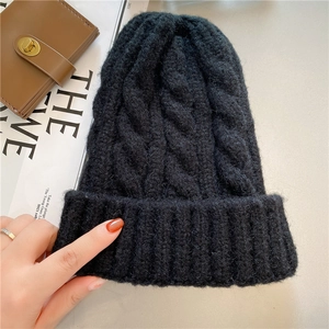 Detail of thick black cable knit beanie with folded brim and premium woolen texture