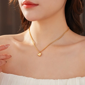 Détail d'un collier double couche avec pendentif cœur doré et pierres scintillantes
