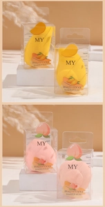 Detail of mango and peach makeup sponges in clear gift boxes for soft application