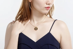 Close-up of gold Hamsa Hand necklace featuring sparkling diamond accents on a round pendant