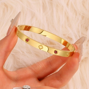 Detail of gold clover bangle featuring pink round gemstones and openwork patterns