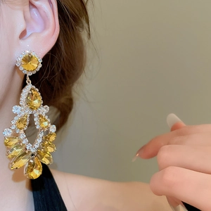 Close-up of elegant amber drop tassel earrings with glittering diamonds on hollow metal