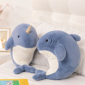 Soft blue narwhal and whale plush toys for girls on a cozy white bed background
