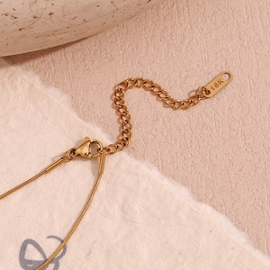 Macro detail of the 18K gold-plated snake chain showing the lobster clasp and quality tag