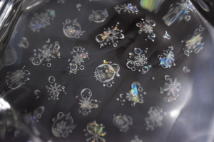 Detailed macro view of holographic white snowflake and moon nail stickers on black base