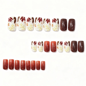 Autumn press-on nails featuring maple leaf patterns and brown glitter gradients