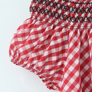 Détail du tissu à carreaux rouge et blanc avec smocks élastiques et coutures noires