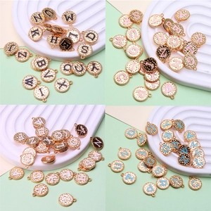 Macro detail of A-Z round enamel alphabet charms in multiple colors on a textured tray