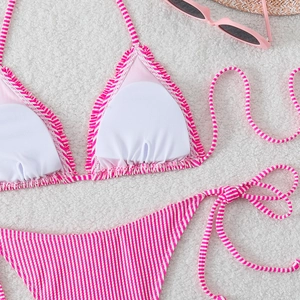 Detailed flat lay of pink and white striped bikini with side-tie bottoms and sunglasses