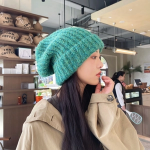 Detailed texture of thick emerald green knit beanie with soft mohair yarn effect