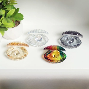 Detail of four colorful crystal seashells with faceted pearls on a clean white shelf