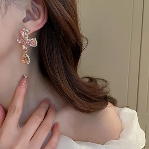 Détail de boucles d'oreilles papillon avec cristal rose et zircon sur profil modèle