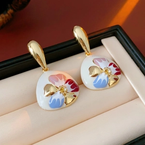 Macro shot of vintage enamel flower earrings in gold and white finish on beige jewelry box