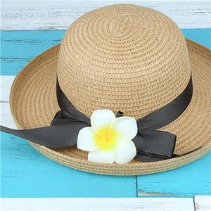Detailed straw sun hat with black ribbon bow and white frangipani flower on top