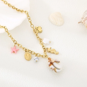 Gold stainless steel necklace with pink starfish, seahorse, and shell charms on beach sand