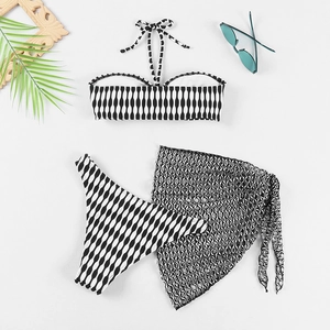 Mise à plat d'un bikini 3 pièces à rayures avec paréo en maille noire et feuille de palmier