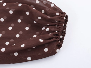 Dettaglio dei polsini elastici su un abito di chiffon a pois marroni con tessuto velato