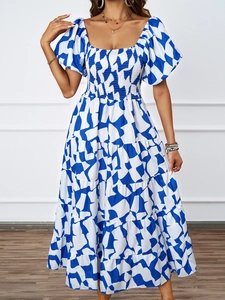 Dettaglio dell'abito lungo con stampa geometrica blu e bianca, gonna a balze e maniche a sbuffo