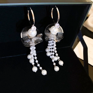 Macro shot of vintage silver earrings with cascading pearls and crystal fringe in a velvet box