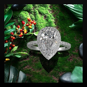Detailed close-up of a pear-cut halo zircon ring placed on natural green moss