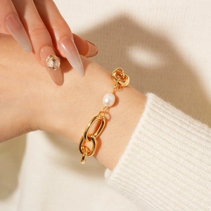 Detail of gold-plated chain bracelet with a single freshwater pearl worn on wrist