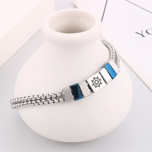 Macro shot of stainless steel double-layer box chain bracelet with blue helm icon detail