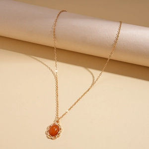 Dettaglio della catena dorata con pendente ovale in agata rossa e croce vintage