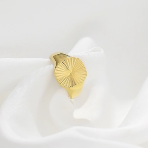 Detailed view of a gold ribbed dome ring featuring textured lines on white silk fabric