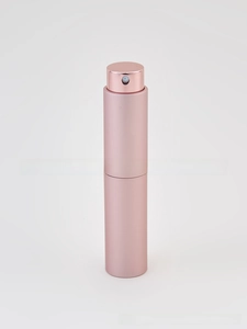 Detailed close-up of pink metallic refillable perfume atomizer with spray nozzle