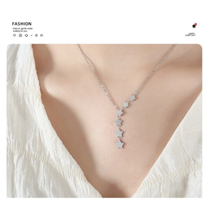Detailed view of silver star tassel necklace pendant on woman's collarbone