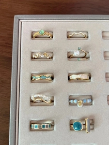 Collection of gold zircon rings with turquoise enamel and pearls in a velvet jewelry box