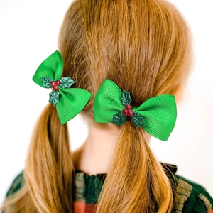 Close-up of a girl wearing green ribbon bow hair clips with holly berry details