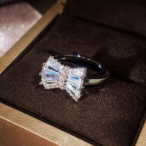 Macro shot of bow-shaped silver ring with clear zircon crystals in a brown jewelry box