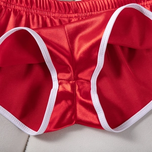 Dettaglio macro dei pantaloncini sportivi in raso rosso con bordi bianchi e elastico