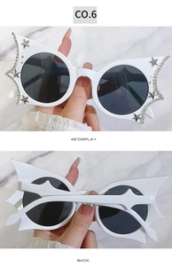 Detail view of white bat-wing sunglasses with sparkling rhinestones and star accents